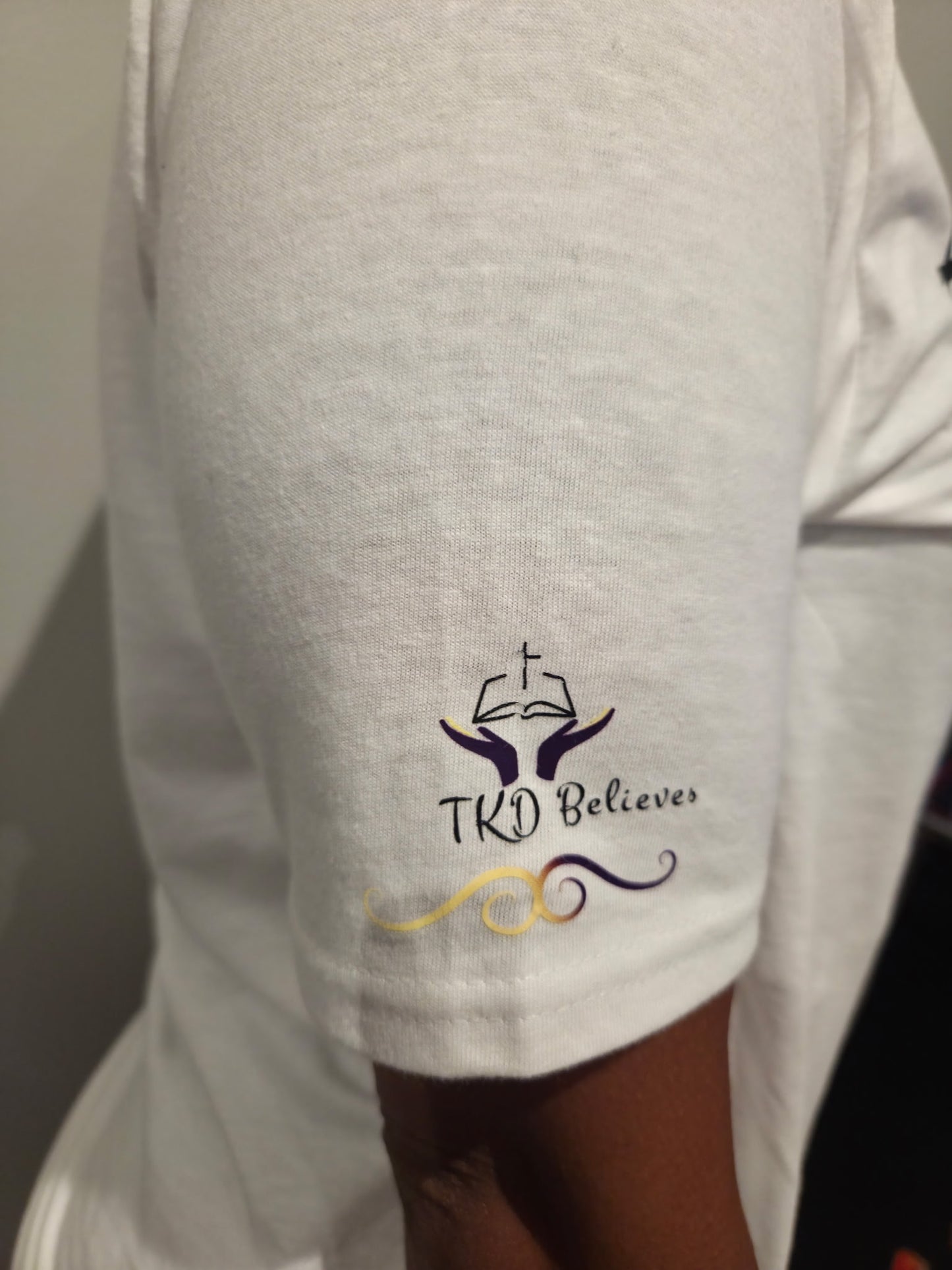 Close-up of TKD believes logo design on Essential Faith T-Shirt - Inspirational Christian clothing on arm