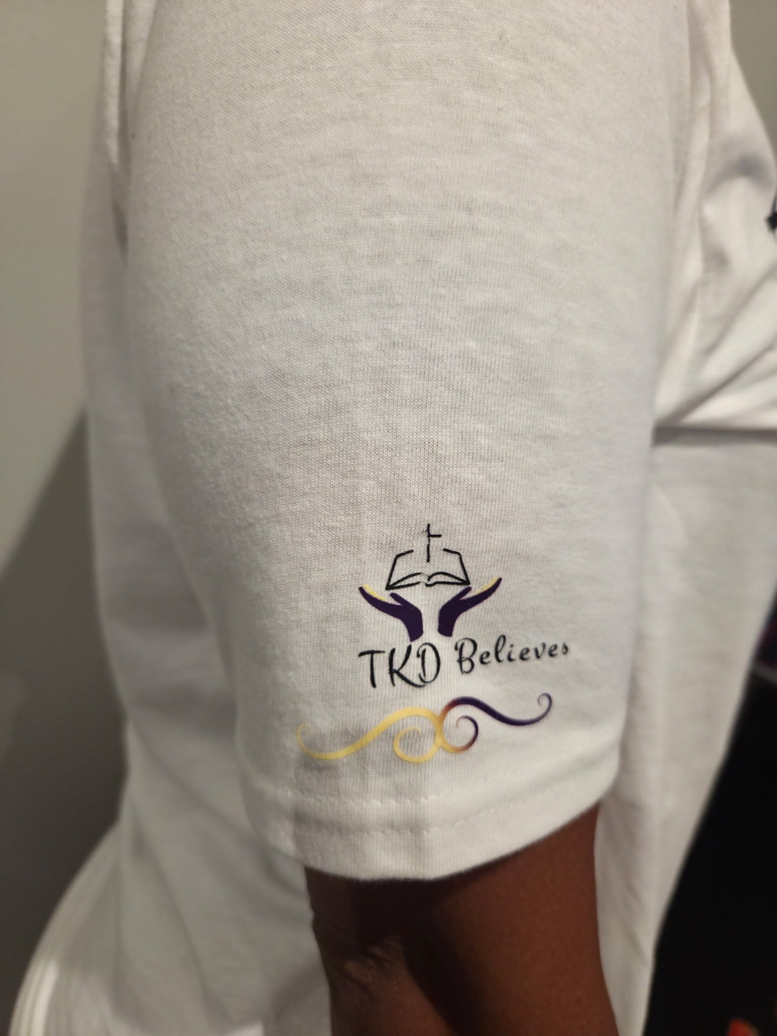 Close-up of TKD believes logo design on Essential Faith T-Shirt - Inspirational Christian clothing on arm